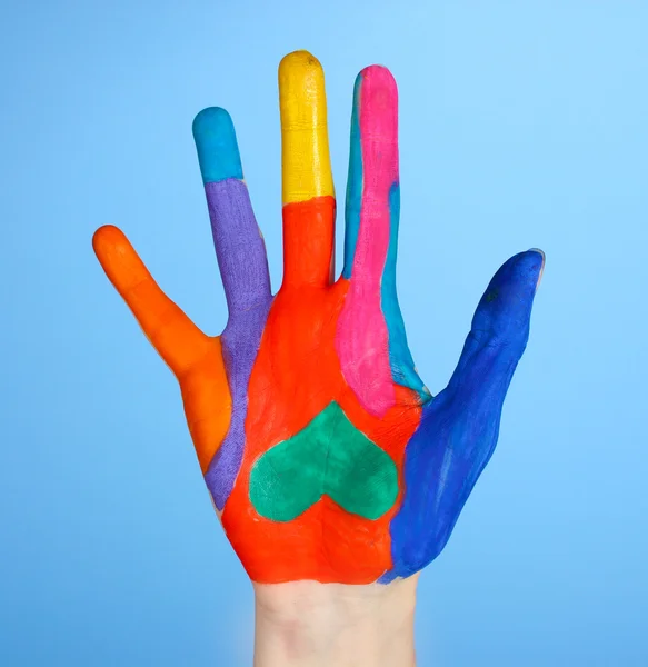 A közeli kék háttér élénk színű kéz — Stock Fotó