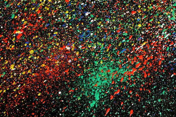 stock image Bright splashes of paint on black background close-up