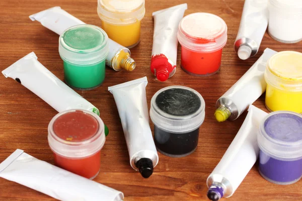 Tubes with colorful watercolors and jars with gouache on wooden table close-up — Stock Photo, Image