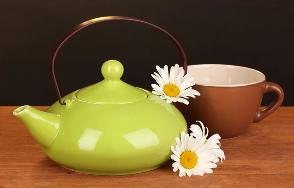 Teiera e tazza con camomilla tè su tavolo di legno su sfondo marrone — Foto Stock