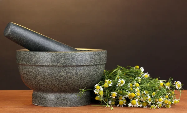 Kamille bloemen in mortel op houten tafel op bruine achtergrond — Stockfoto