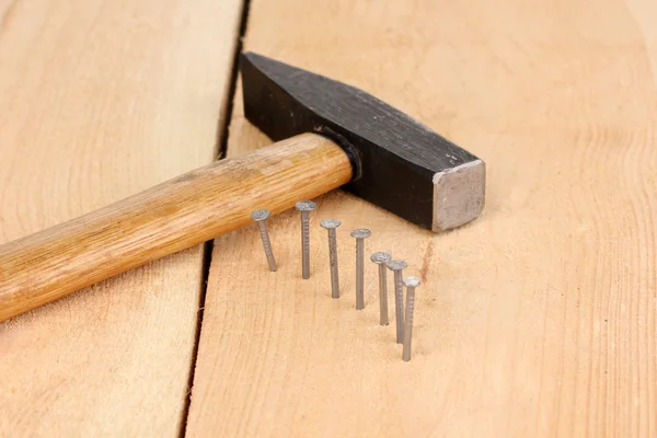 Clavos de metal en tablón de madera y martillo — Foto de Stock