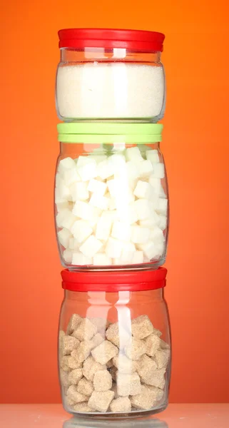 Gläser mit braunem Rohrzuckerklumpen, weißem Kristallzucker und weißem Klumpen Zucker auf buntem Hintergrund — Stockfoto