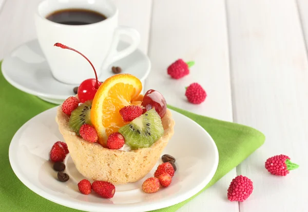 Süßer Kuchen mit Früchten auf Teller und Kaffee auf Holztisch — Stockfoto