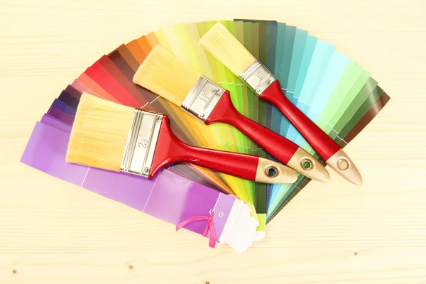 Pincéis de pintura e paleta brilhante de cores sobre fundo de madeira — Fotografia de Stock