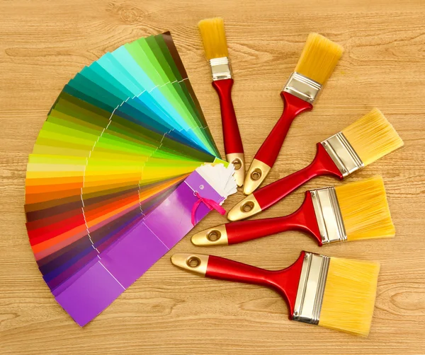 Paint brushes and bright palette of colors on wooden background Royalty Free Stock Images