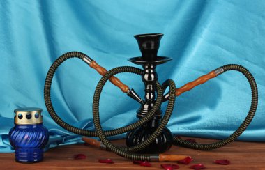 Hookah on a wooden table on a background of blue curtain close-up clipart