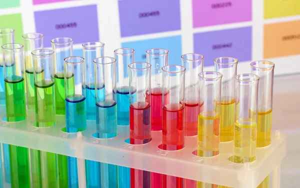 Tubos de ensayo con líquido de color sobre fondo de muestras de color — Foto de Stock