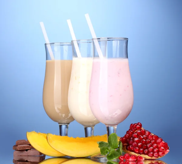 Milchshakes mit Früchten und Schokolade auf blauem Hintergrund — Stockfoto