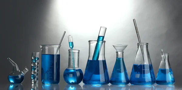 Tubos de ensaio com líquido azul sobre fundo cinzento — Fotografia de Stock