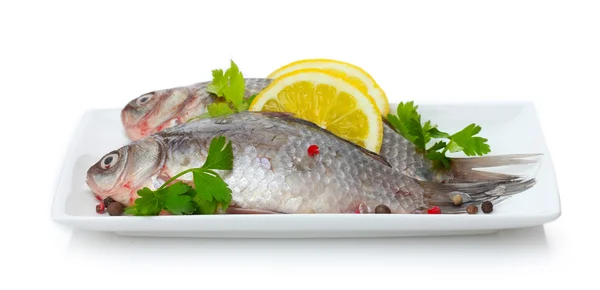 Frische Fische mit Zitrone und Petersilie auf Teller isoliert auf weiß — Stockfoto