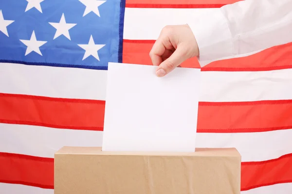 Hand with voting ballot and box on Flag of USA — Stock Photo, Image