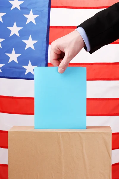 Mano con voto e scatola sulla Bandiera degli Stati Uniti — Foto Stock