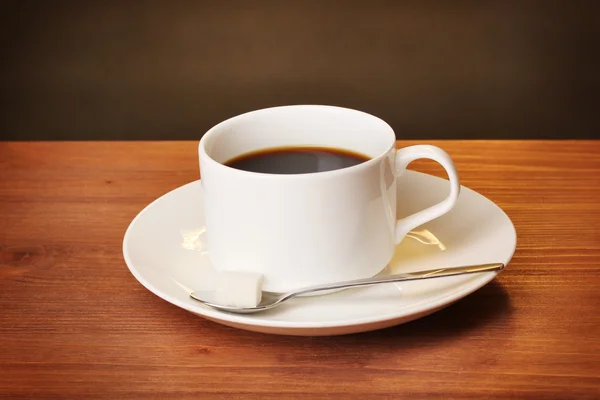 Filiżanka kawy na drewnianym stole na brązowym tle — Zdjęcie stockowe