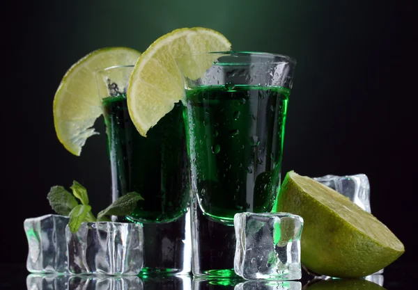 Two glasses of absinthe, lime and ice on green background — Stock Photo, Image