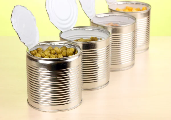 打开豌豆、 玉米、 豆和豆绿色背景上的木桌上的锡罐 — 图库照片