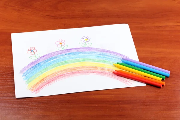 Dibujo infantil de arco iris y lápices sobre fondo de madera — Foto de Stock