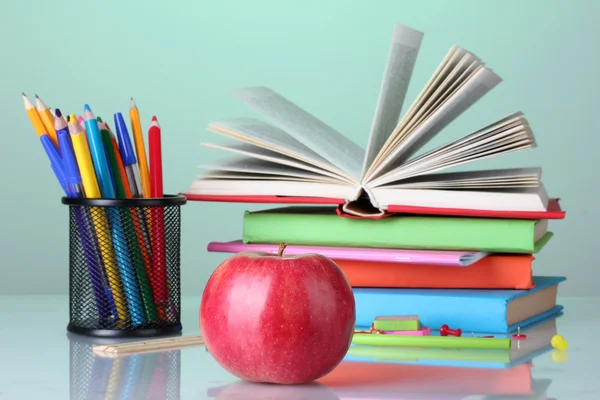 Sammansättningen av böcker, pappersvaror och ett äpple på ljusa färgglada bakgrund — Stockfoto