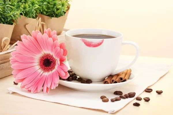 Tasse Kaffee mit Lippenstift und Gerberabohnen, Zimtstangen auf Holztisch — Stockfoto