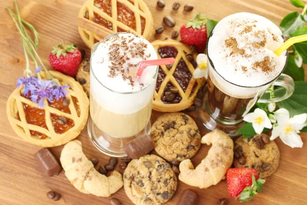 Bicchieri di cocktail di caffè su tavolo di legno con dolce e fiori — Foto Stock