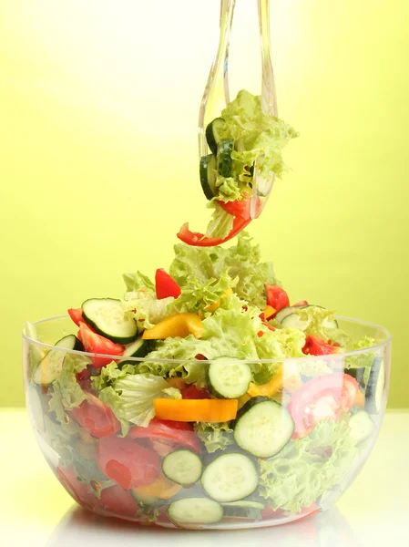 Salada de legumes frescos em tigela transparente com colher e garfo no fundo verde — Fotografia de Stock