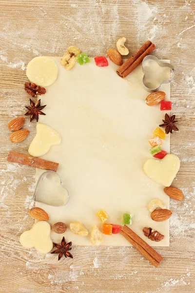 Rahmen aus kandierten Früchten, Nüssen, ungebackenen Keksen und Formen für Plätzchen auf Pergament in Nahaufnahme — Stockfoto