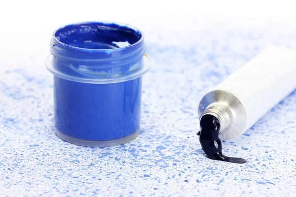 Pot met blauwe gouache en buis met blauwe waterverf op achtergrond van blauwe spray close-up — Stockfoto