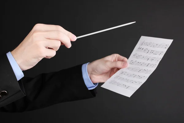 Manos de director de música con bastón y notas aisladas en negro — Foto de Stock
