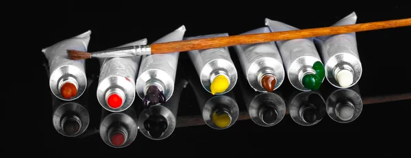 Tubi con un acquerello colorato luminoso con pennello su sfondo nero primo piano — Foto Stock
