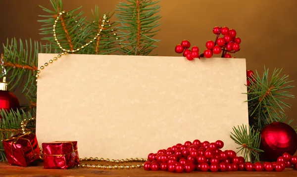 Lege briefkaart, kerstballen en Spar-boom op houten tafel op bruine achtergrond — Stockfoto