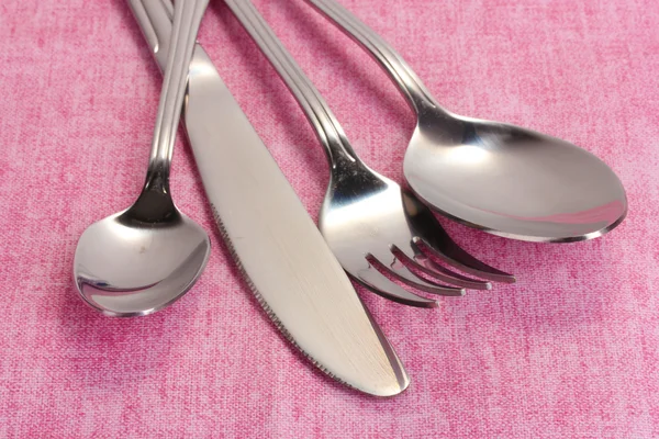 Garfo, colher e faca em uma toalha de mesa rosa — Fotografia de Stock