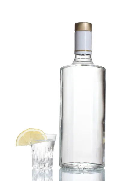 Bottiglia di vodka e bicchiere da vino con limone isolato su bianco — Foto Stock