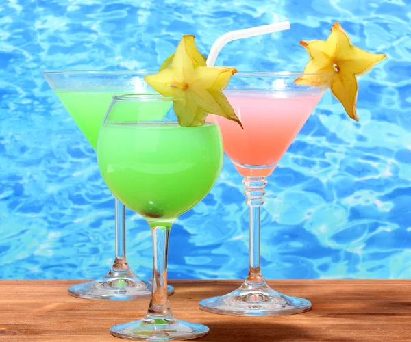 Glasses of cocktails on wooden table on blue sea background — Stock Photo, Image