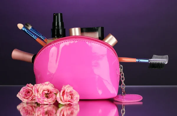 Make up bag with cosmetics and brushes on violet background — Stock Photo, Image
