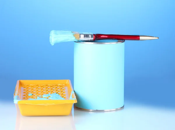 Can of paint with paintbrush and tray with blue paint on blue background — Stock Photo, Image
