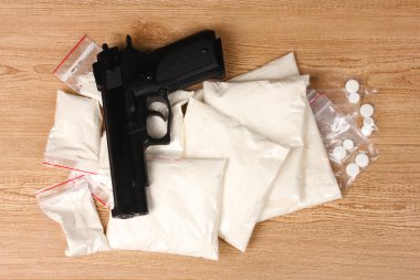 Cocaine and marihuana in packages and handgun on wooden background clipart