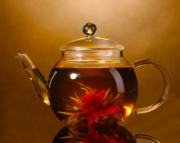 Théière en verre et tasse avec thé vert exotique sur table en bois sur fond brun — Photo