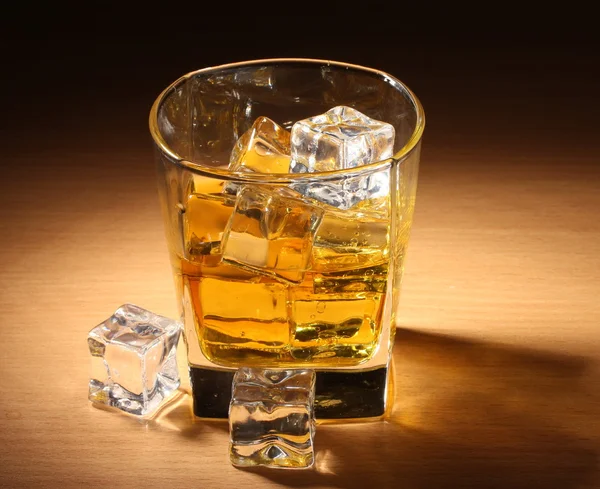 Glass of scotch whiskey and ice on wooden table — Stock Photo, Image