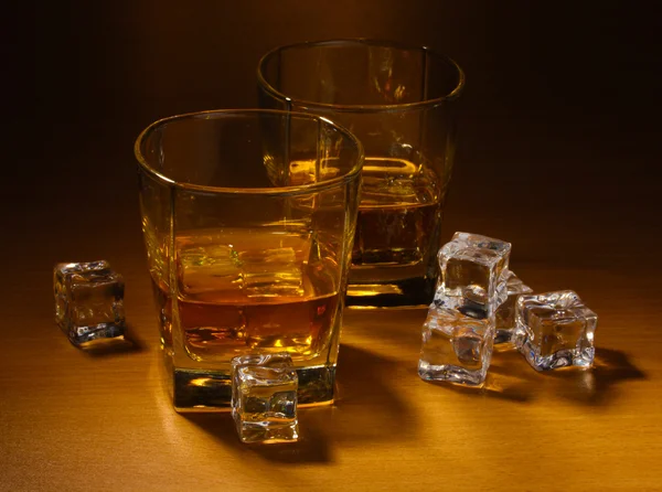 Due bicchieri di whisky scozzese e ghiaccio sul tavolo di legno — Foto Stock