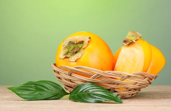 用叶子垫在绿色背景上的木桌上的开胃柿子 — 图库照片