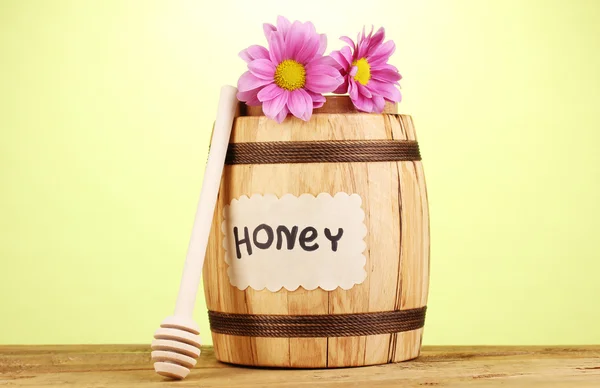 Γλυκό μέλι στο βαρέλι με drizzler στο ξύλινο τραπέζι σε πράσινο φόντο — Φωτογραφία Αρχείου