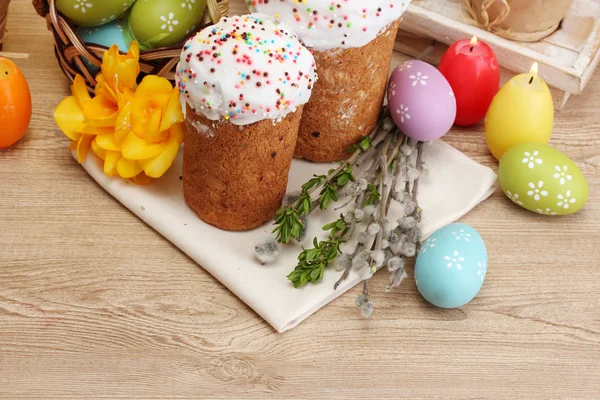 Beaux gâteaux de Pâques, œufs colorés dans le panier et bougies sur table en bois — Photo