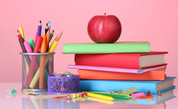 Sammansättningen av böcker, pappersvaror och ett äpple på ljusa färgglada bakgrund — Stockfoto