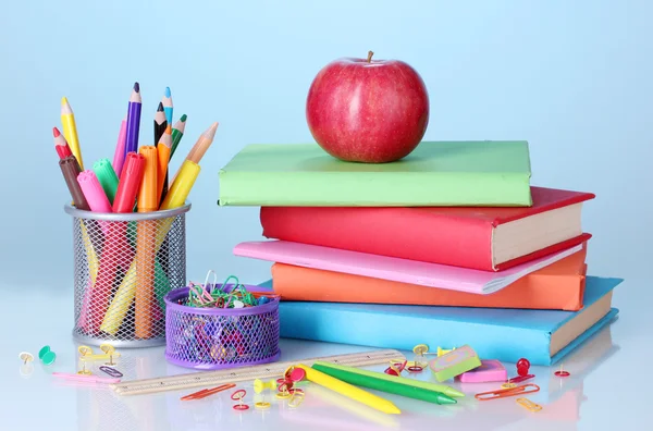 Composición de libros, papelería y una manzana sobre fondo de colores brillantes — Foto de Stock
