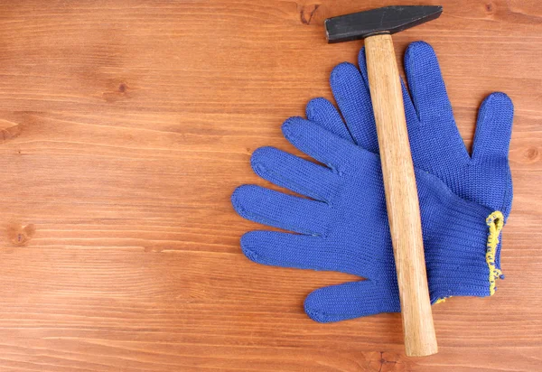 Hammer und Handschuhe auf Holzgrund — Stockfoto