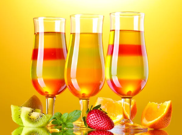 Fruit jelly in glasses and fruits on yellow background — Stock Photo, Image