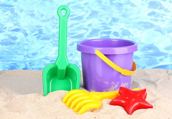 水の背景に砂の上の子供のビーチおもちゃ — ストック写真