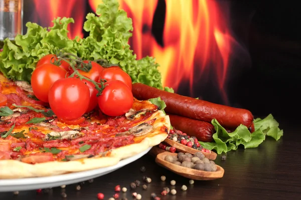 Lezzetli pizza ve ahşap masa üzerinde alev arka plan domates — Stok fotoğraf
