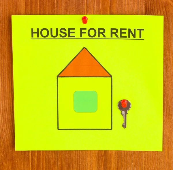 Cartaz sobre alugar a casa com a chave no fundo de madeira — Fotografia de Stock