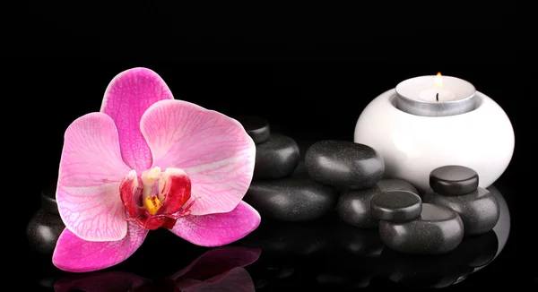 Pietre termali con fiore di orchidea e candela isolate su nero — Foto Stock
